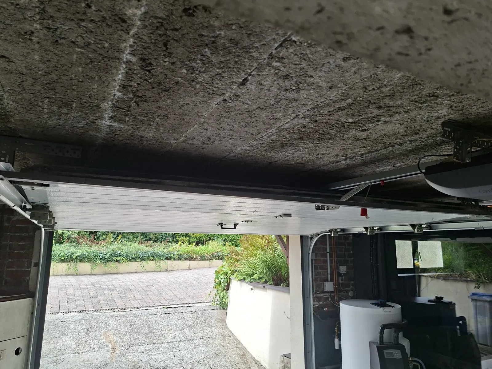 avant l'isolation du plancher bas à Faumont : dalle béton brute au plafond du garage, porte sectionnelle ouverte